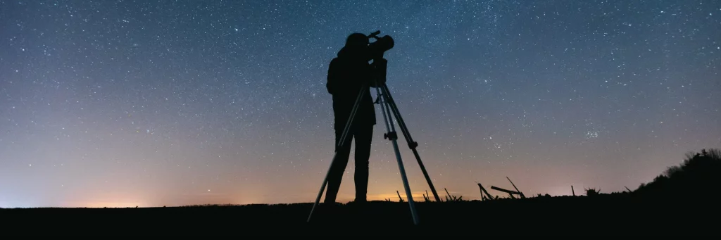 pessoa olhando o céu com telescópio